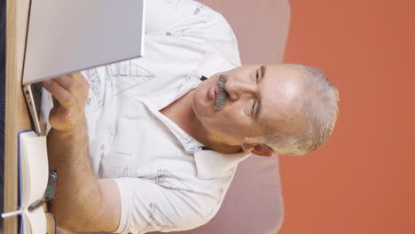 Vertical-video-of-Old-man-working-on-laptop-with-happy-expression.